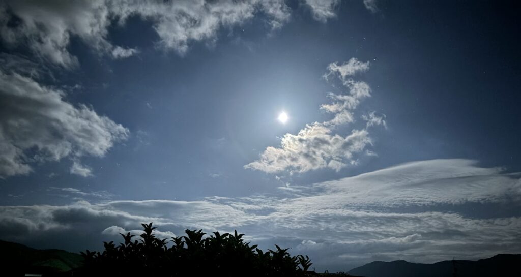 青い夜空に浮かぶ月と流れる雲