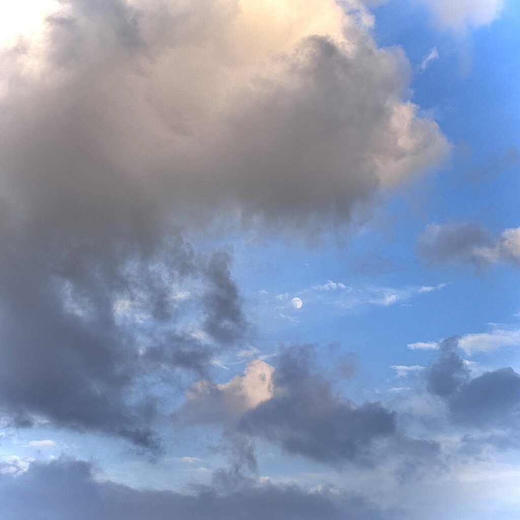 青空に浮かぶ昼の月と雲
