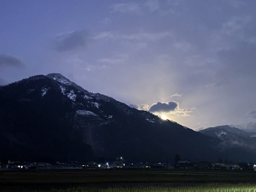 山の向こうから光が差し込む夕方の空
