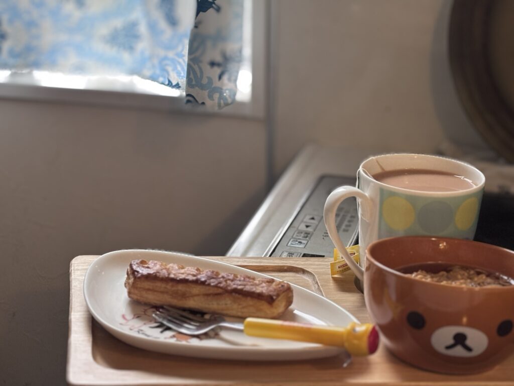 朝の光が差し込む窓辺で、さつまいもデニッシュとミニラーメン、ミルクティーを楽しむ朝食